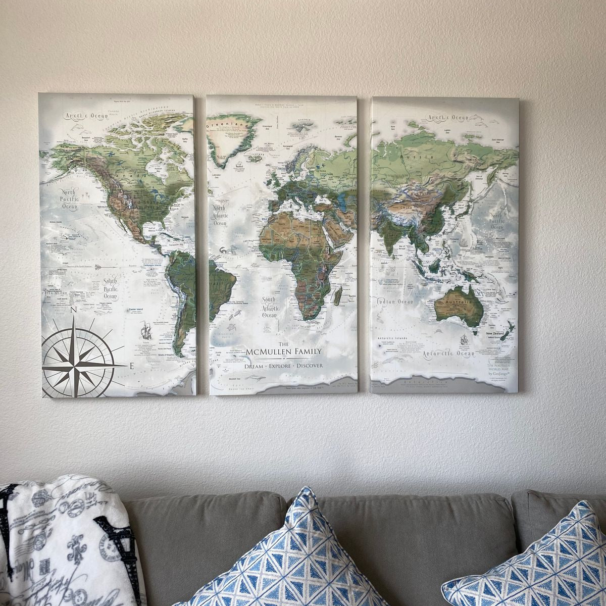 Three panel world push pin travel map hanging above a couch