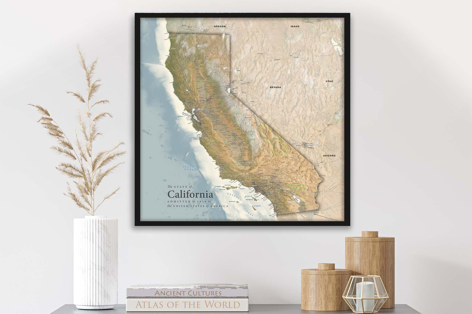 Travel map of California in a black frame on a wall above a shelf