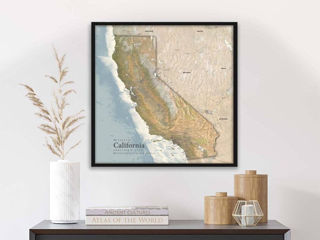 Travel map of California in a black frame on a wall above a shelf