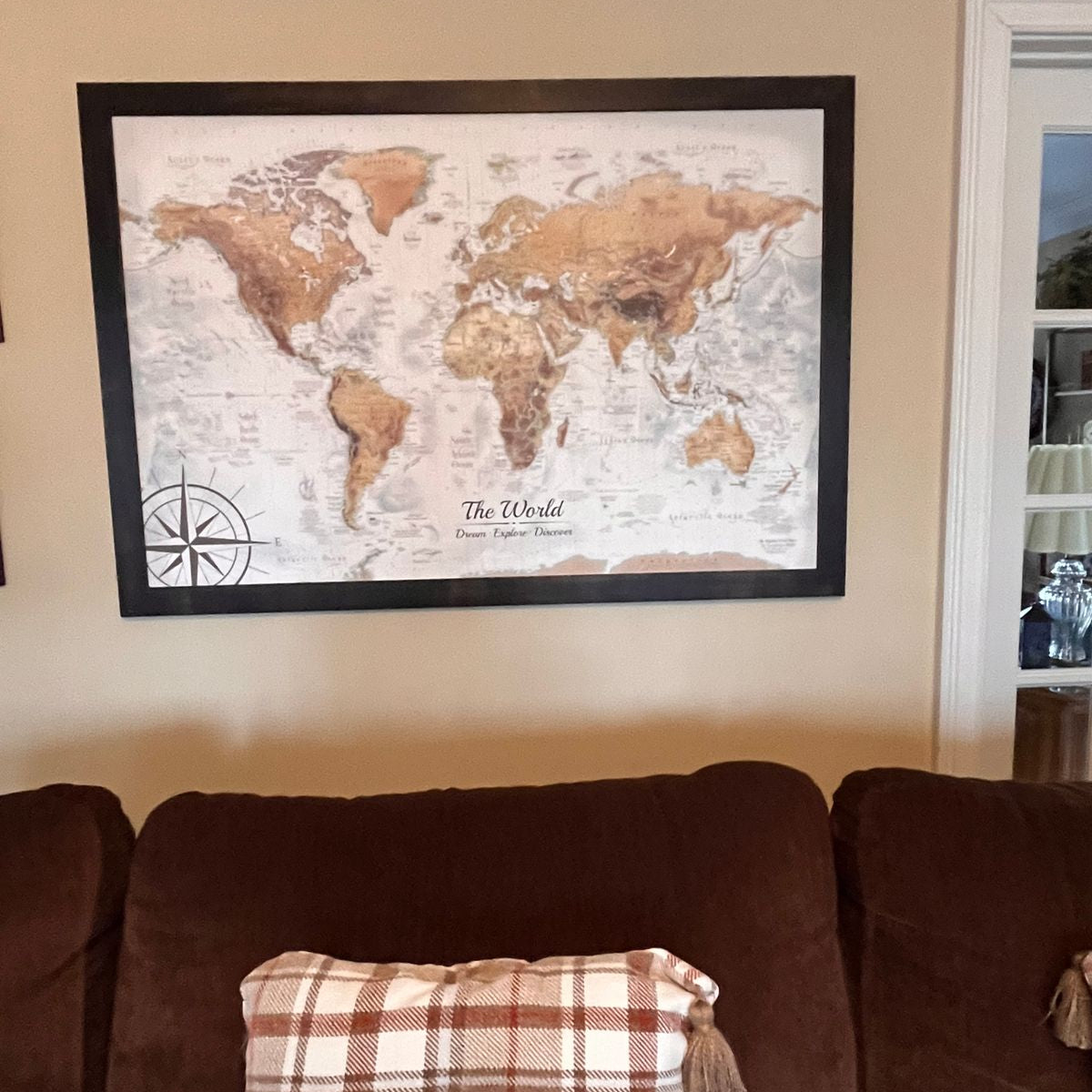 Magellan World Push Pin Travel Map Framed hanging above a couch