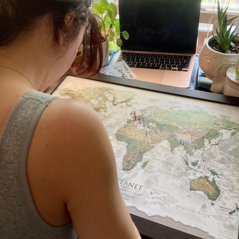 Person pinning their world travel map with pins