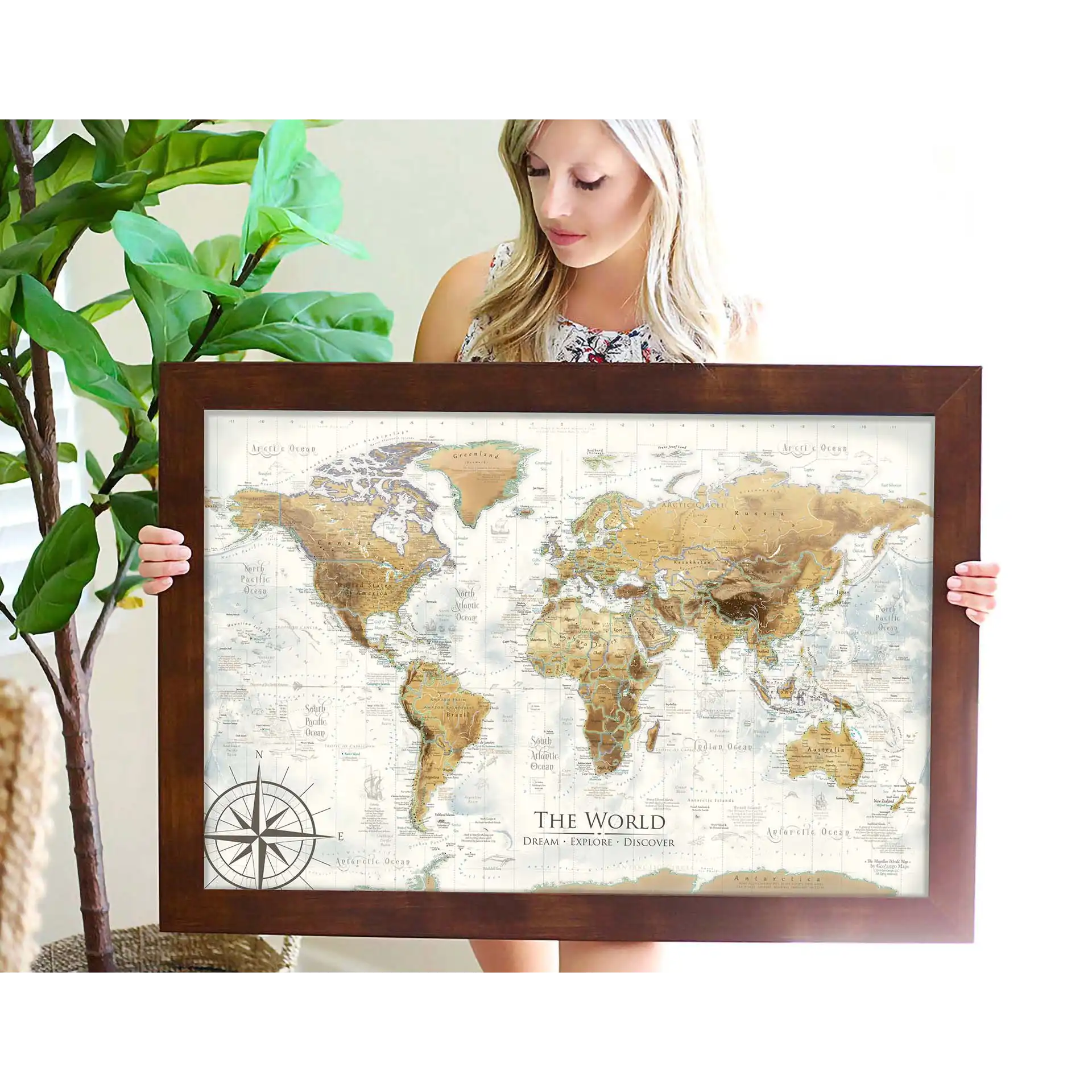 person holding an antique world map framed in walnut