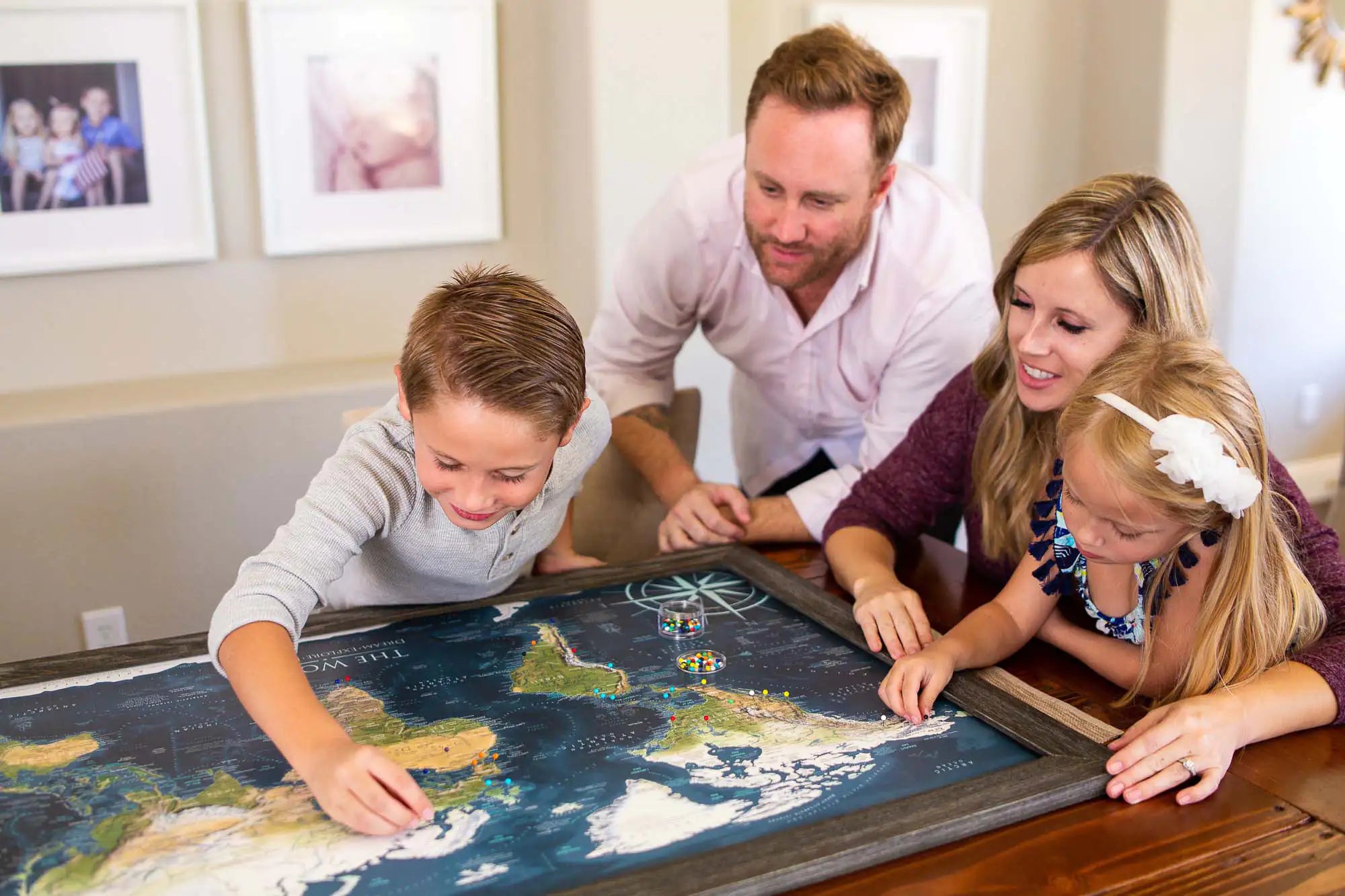 Family pinning their vacations on a Framed World Push Pin Travel Map.
