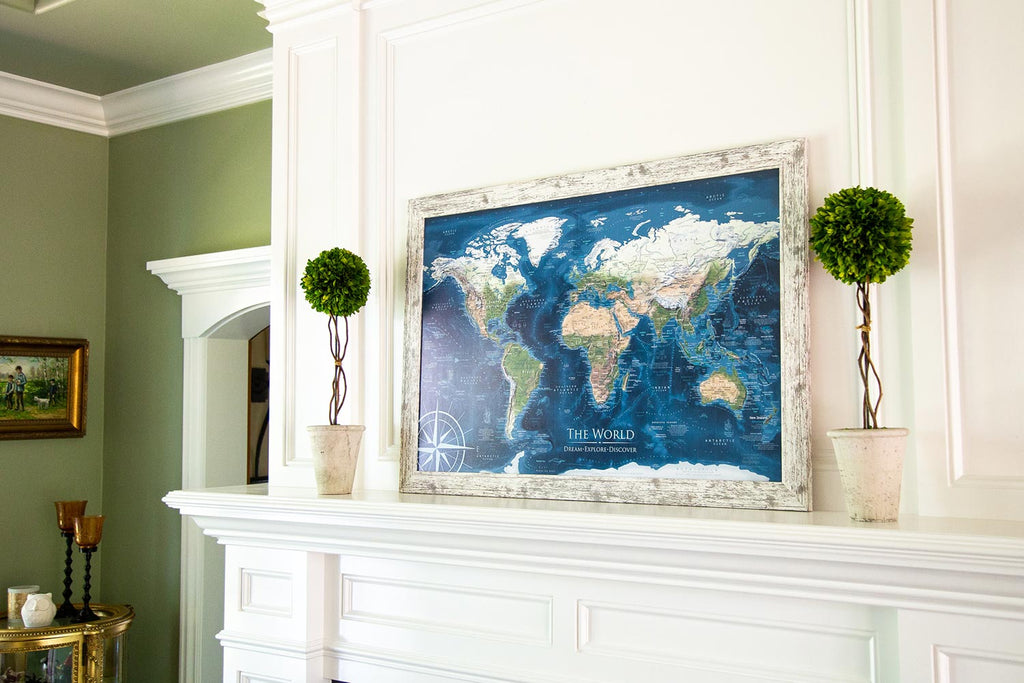 The Voyager Travel Map in a green room on a white mantle surrounded by beautiful topiary