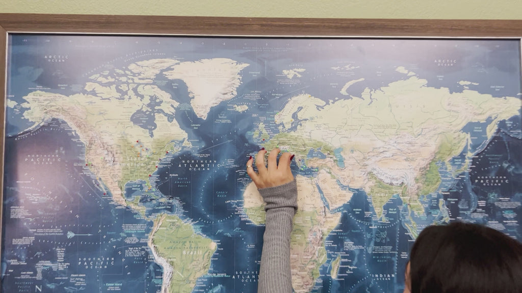 Person pinning their voyager push pin map of the world