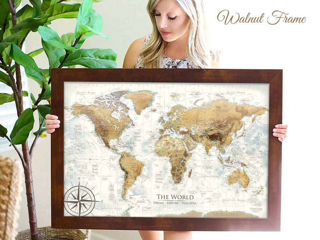 person holding an antique world map framed in walnut