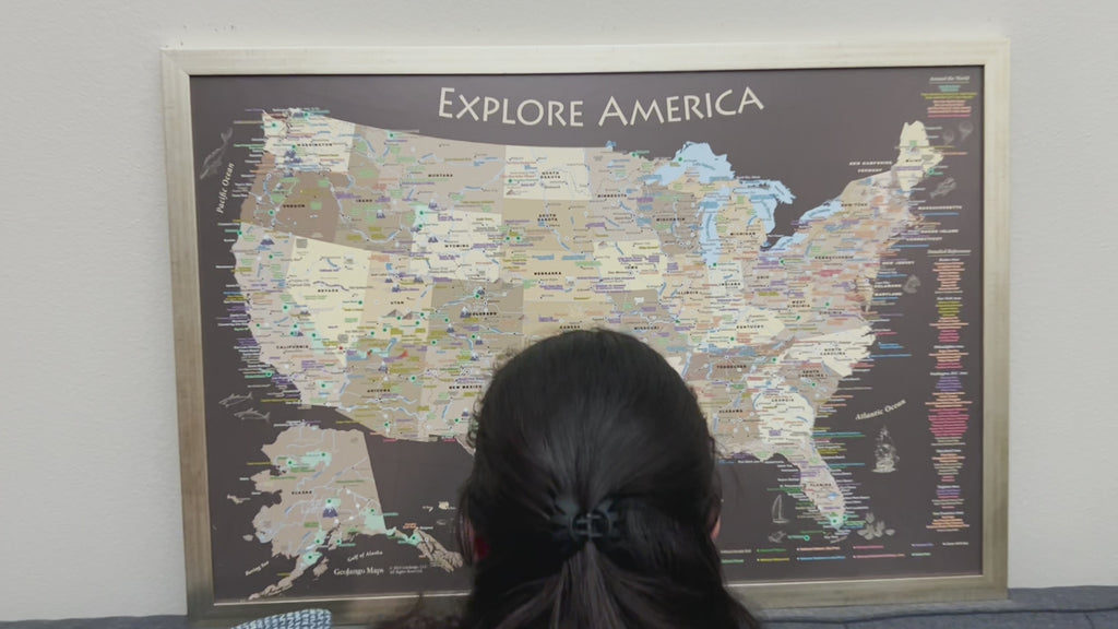 Video showing person pinning a USA national parks push pin travel map framed