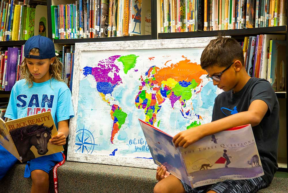 Kids in a library with a world map with pins